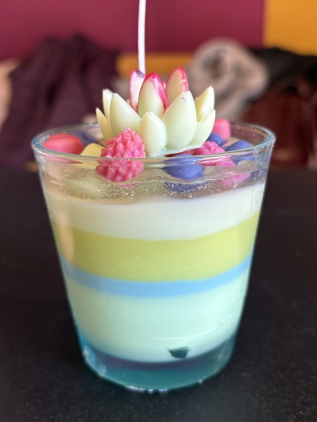 Vela de soja en vaso de cristal con capas de colores hecha en un taller